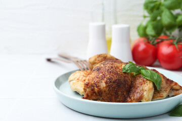Tasty roasted chicken thighs with basil served on white tiled table, closeup. Space for text