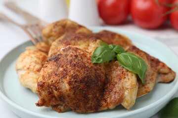 Tasty roasted chicken thighs with basil served on white table, closeup