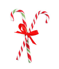 Tasty candy canes with bow isolated on white, top view. Christmas treat