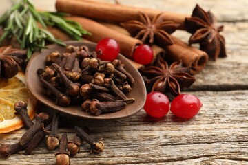 Different spices, cranberries, fresh rosemary and dry orange slice for mulled wine on wooden table, closeup