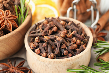 Mulled wine spices. Cloves in wooden bowl, rosemary, anise stars and cinnamon sticks on table, closeup