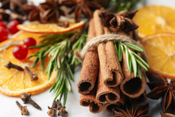 Different spices, dry orange slices, cranberries and fresh rosemary for mulled wine on light table, closeup