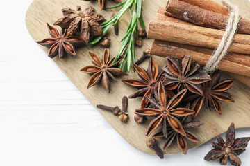 Mulled wine spices. Anise stars, cinnamon sticks, cloves and fresh rosemary on white wooden table,...