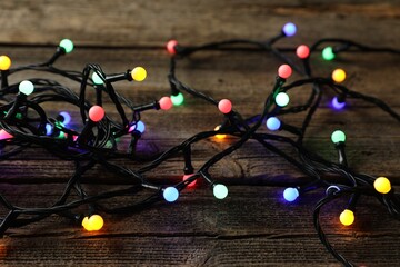 Bright Christmas lights on wooden table, closeup