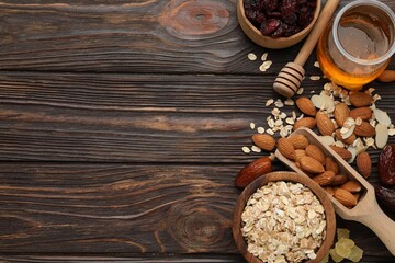 Making granola. Oat flakes, dried fruits and other ingredients on wooden table, flat lay. Space for text
