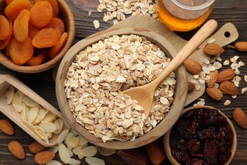Making granola. Oat flakes, dried fruits and other ingredients on wooden table, flat lay