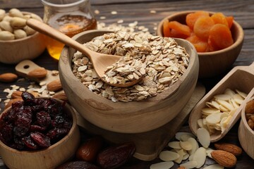 Making granola. Oat flakes, dried fruits and other ingredients on wooden table, closeup