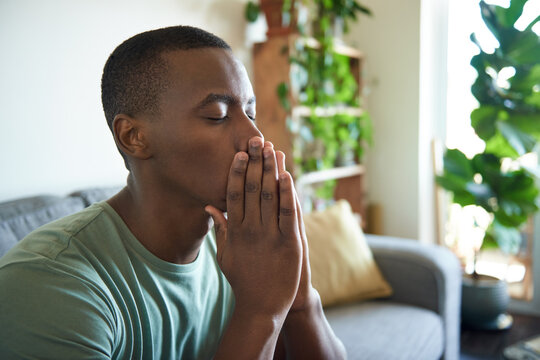Depressed young African man sitting with his eyes closed