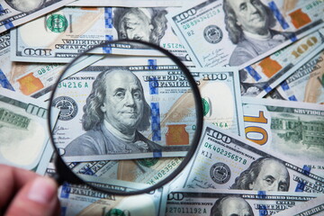 Magnifying glass on one hundred US dollars banknotes. Close up.