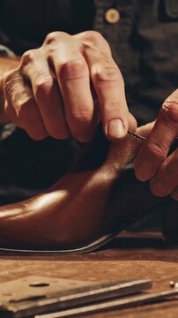 cobbler hand-polishing leather shoe on workbench, skilled fingers buffing sole and stitching edges, vintage