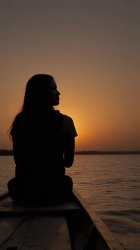 Ideal for travel promotions, the serene silhouette image captures a woman in a boat at sunset by varanasi river. Perfect for tourism ads, blog posts, and inspirational design projects.