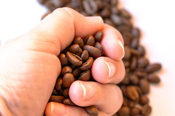 Hand cradles roasted coffee beans in soft light; selective focus highlights texture and aroma, suggesting morning ritual, barista craft and natural coffee lifestyle stories.