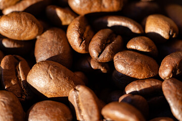 Extreme macro of roasted coffee beans shows rugged surface and glossy patina; selective focus delivers a bold gourmet backdrop for packaging, menus and natural coffee lifestyle themes.