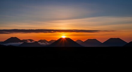 Dramatic sunrise over silhouetted mountains creating a stunning landscape.