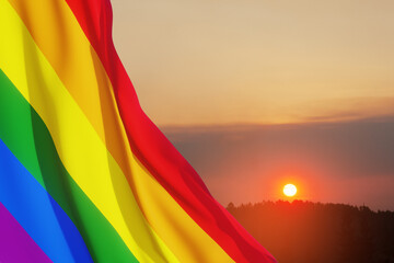 Waving LGBT pride flag on sunset sky, rainbow flag background. Multicolored peace flag movement. Original colors symbol.