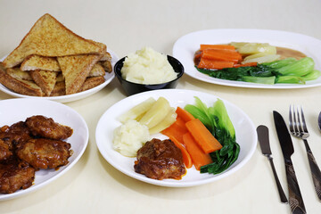 Minced pork hamburger patty, mashed potatoes, cheese bread, vegetables with sauce, arranged on a dining table.


