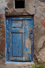 Rustic door with peeling blue paint highlights weathered texture and aged wood