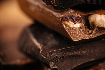 Close-up macro of stacked chocolate pieces with whole nuts showing rich texture and soft warm tones perfect for dessert branding and confectionery advertising