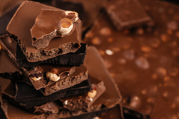 Stacked broken chocolate pieces with nuts in warm soft focus creating a rich artisan dessert scene...