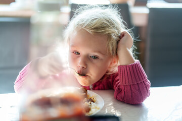 Young girl enjoying a meal at home while lost in thought on a sunny afternoon