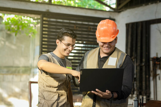 Carpentry boss showing computer to colleague in the workshop. Carpentry Workshop manager using the computer to teach a worker