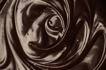 Close-up swirl of melted glossy dark chocolate creating smooth rich texture perfect for dessert design, confectionery branding and sweet food advertising backgrounds