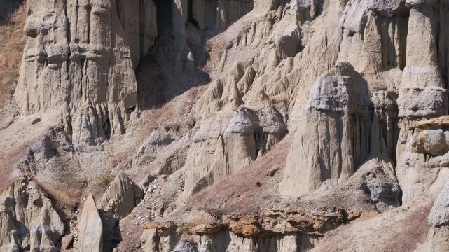 Fairy chimneys at Kula, Turkey. Impressive rock formations on a hillside, surrounded by lush greenery, highlighting the natural beauty and rugged terrain of the landscape.