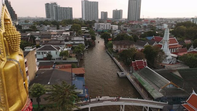 Aerial view of golden buddha statue at wat paknam phasi charoen temple, revealing sprawling Bangkok cityscape, Thailand.