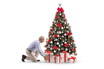 Elderly man putting a present under a Christmas tree