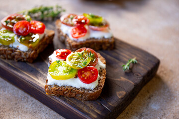 Bruschetta with cream cheese, cherry tomatoes on toasted bread close up