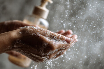 Fototapeta premium Hands washing with soap and water while droplets splash against a blurred background