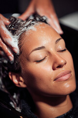 A person enjoying a relaxing hair wash, with closed eyes and a serene expression, as their hair is lathered with shampoo.