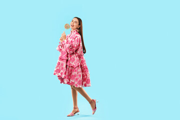 Beautiful woman with lollipop on light blue background