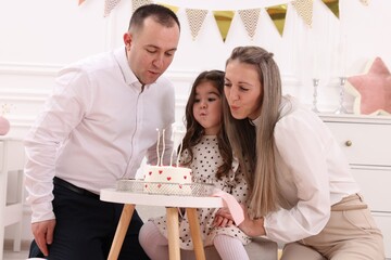 Birthday celebration. Happy family blowing out candles on tasty cake together at home