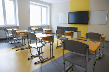 Stylish classroom with desks, chairs and tv at school