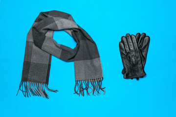 Elegant Winter Accessories: Gray Scarf and Black Leather Gloves on Vibrant Blue Background