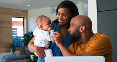 African American Family With Baby Daughter Using Laptop To Check Finances At Home