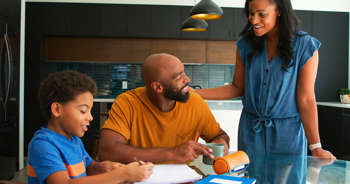 African American Parents Helping Son Studying Homework In Kitchen