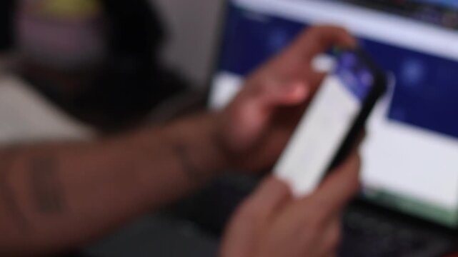 Abstract Blurred Background of Hands Using a Smartphone in Front of a Laptop, Representing Digital Connectivity