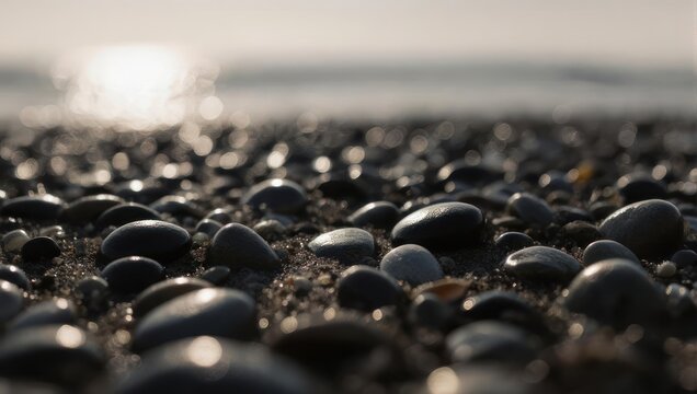 Close-up of smooth dark pebbles on a beach with a bright sun reflection on the water in the background. - Powered by Adobe