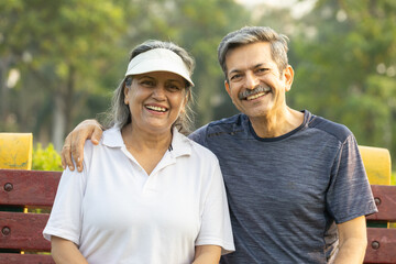 Happy Indian Senior Couple Relaxing and Laughing on Park Bench After Workout