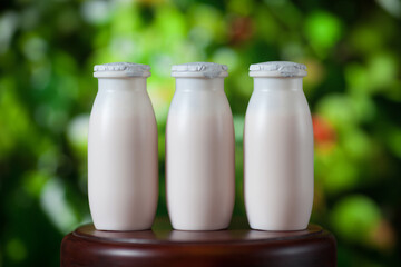 Natural liquid yogurt with probiotics in small plastic bottles on wooden table on background of green trees on a sunny day. Healthy, balanced diet food, healthy breakfast, dairy products.