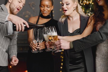 Male and female friends in elegant dresses celebrating New Year