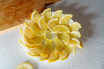 Fresh lemon slices arranged beautifully on a white plate beside a wooden cutting board in a bright kitchen