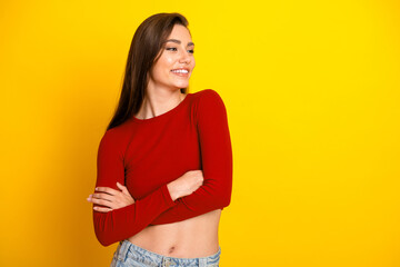 Young woman wearing red crop top smiling against bright yellow background for fashion lifestyle...