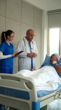 Vertical doctor man and assistant physician woman visiting patient man with brain cancer to diagnostic and examination at hospital, healthcare doctor talking to patient for treatment support.
