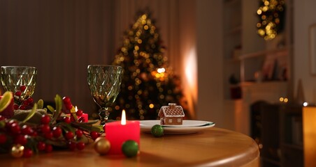 Christmas table setting with plates, glasses and burning candles in festive decorated room. Bokeh effect