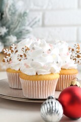 Tasty cupcakes with Christmas decor and gingerbread cookies on white table, closeup