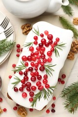 Tasty Christmas cake with cranberries and rosemary served on light table, flat lay