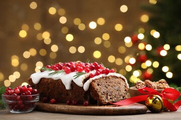 Tasty Christmas cake with icing, cranberries and rosemary on wooden table against background with blurred lights, closeup